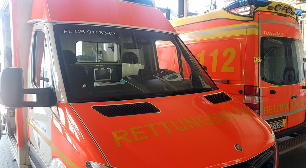 Zwei Rettungswagen in gelb orange stehen in der Feuerwache,