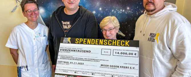 Ein Spendenscheck wird an vier Menschen übergeben