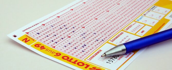 Zu sehen ist ein Lottoschein mit ausgefüllten Zahlen und daneben liegt ein Kugelschreiber.