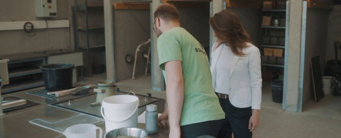 Zwei Menschen stehen nebeneinander. Vor ihnen liegt Beton.