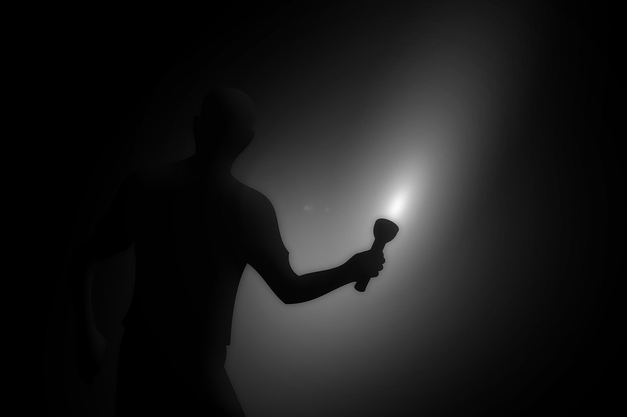 Ein Mann steht im dunkeln mit einer Taschenlampe in der Hand