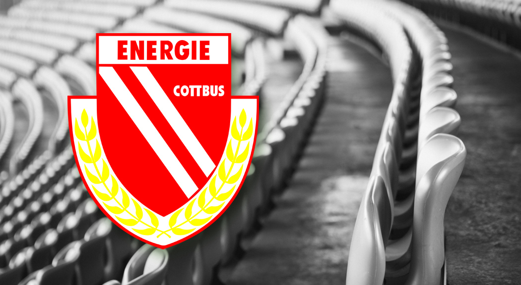 Das Bild zeigt das Logo des FC Energie Cottbus und leere Sitze im Stadion.