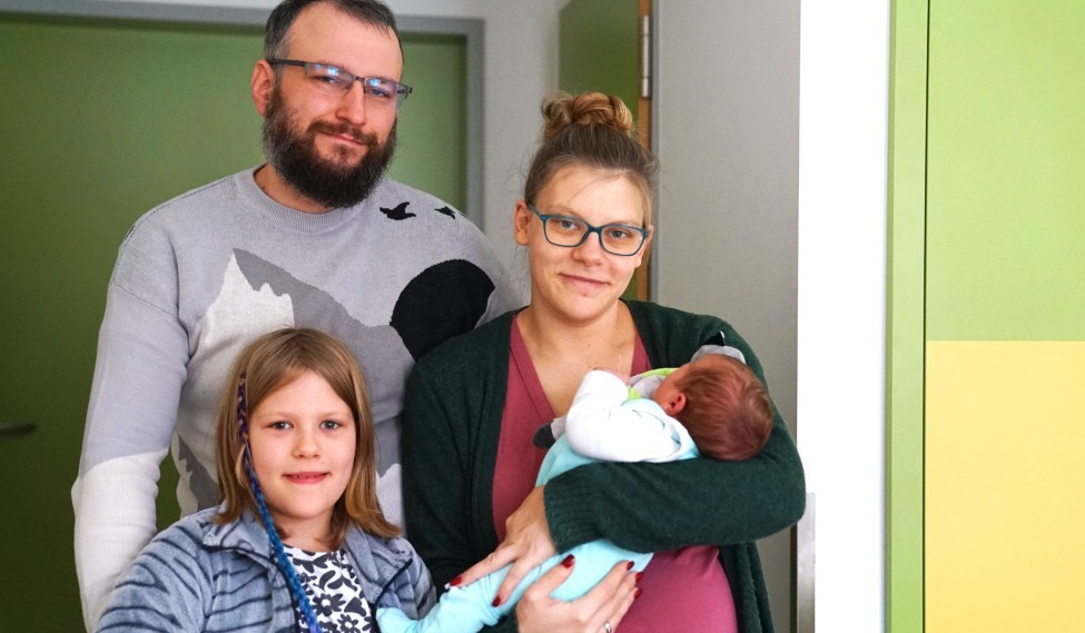 Neujahrsbaby Eine Familie mit einer kleinen Tochter und einem Baby auf dem Arm sind zu sehen.