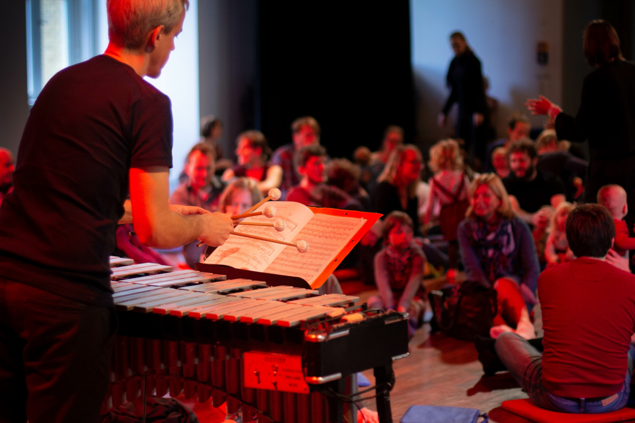 Das Foto zeigt einen Dirigenten bei der Arbeit mit einem Orchester.