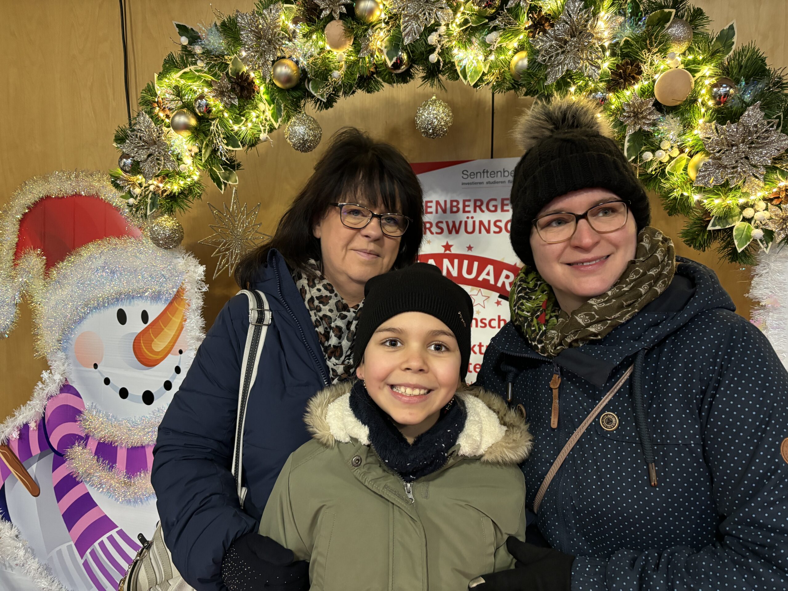 Auf dem Bild ist ein Schneemann und zwei Frauen und ein Kind zu sehen.