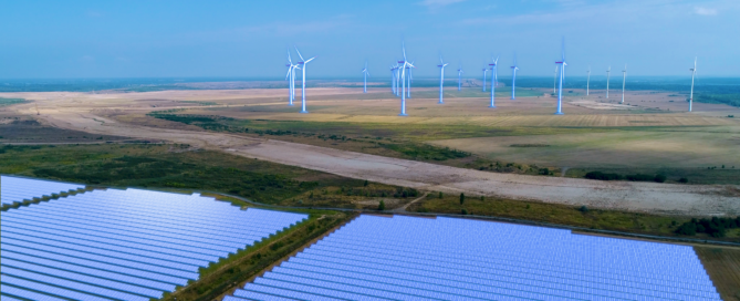 Windräder stehen im Hintergrund. Im Vorderfeld sind Solaranlagen zu sehen.