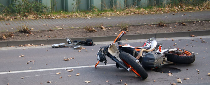 Auf dem Foto ist ein auf der Straße liegendes Motorrad zu sehen, das offensichtlich bei einem Unfall beschädigt wurde.