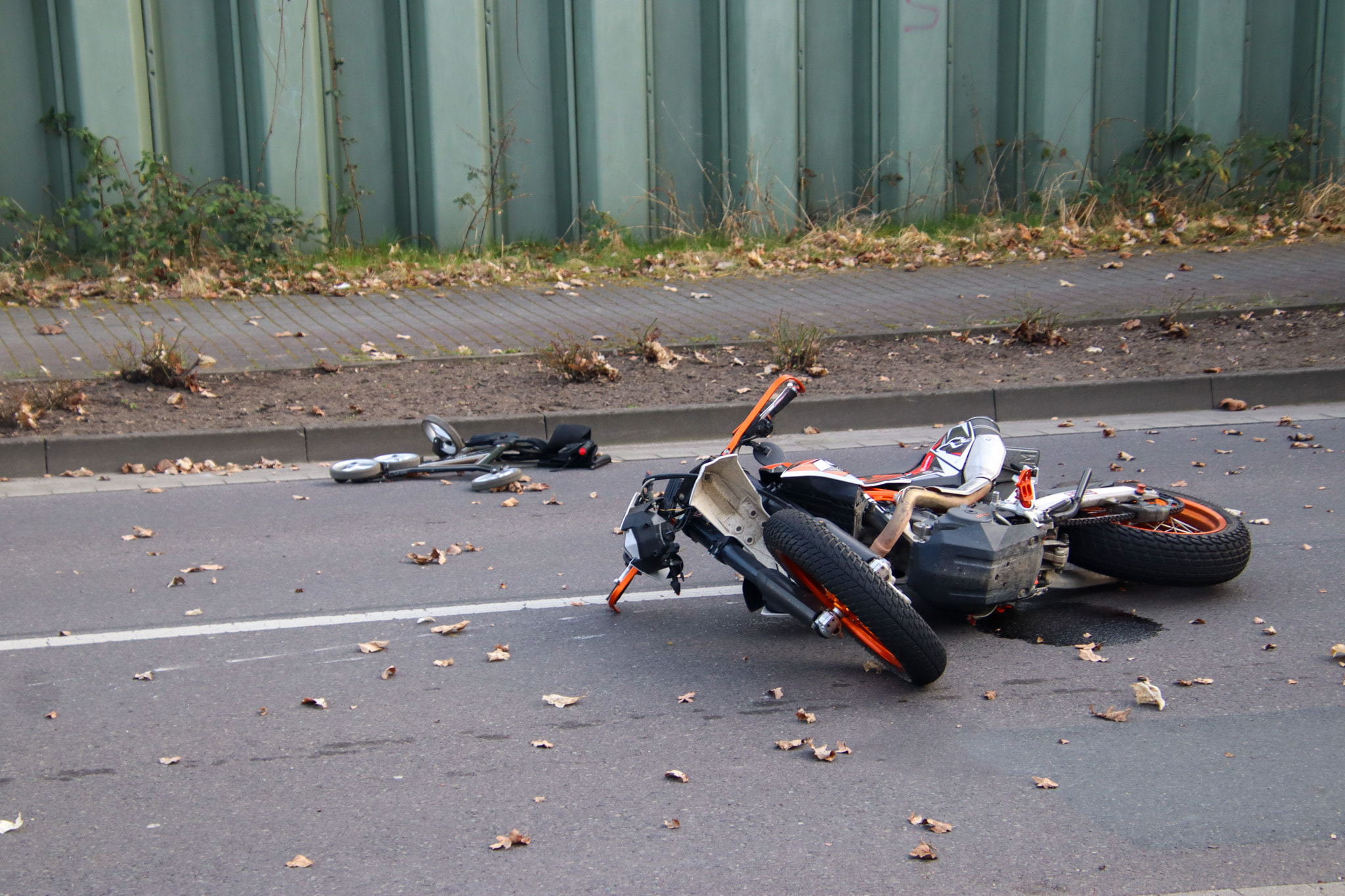 Auf dem Foto ist ein auf der Straße liegendes Motorrad zu sehen, das offensichtlich bei einem Unfall beschädigt wurde.