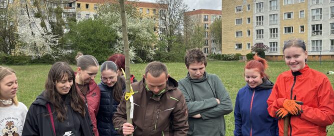 Schülerinnen und Schüler pflanzen einen Apfelbaum