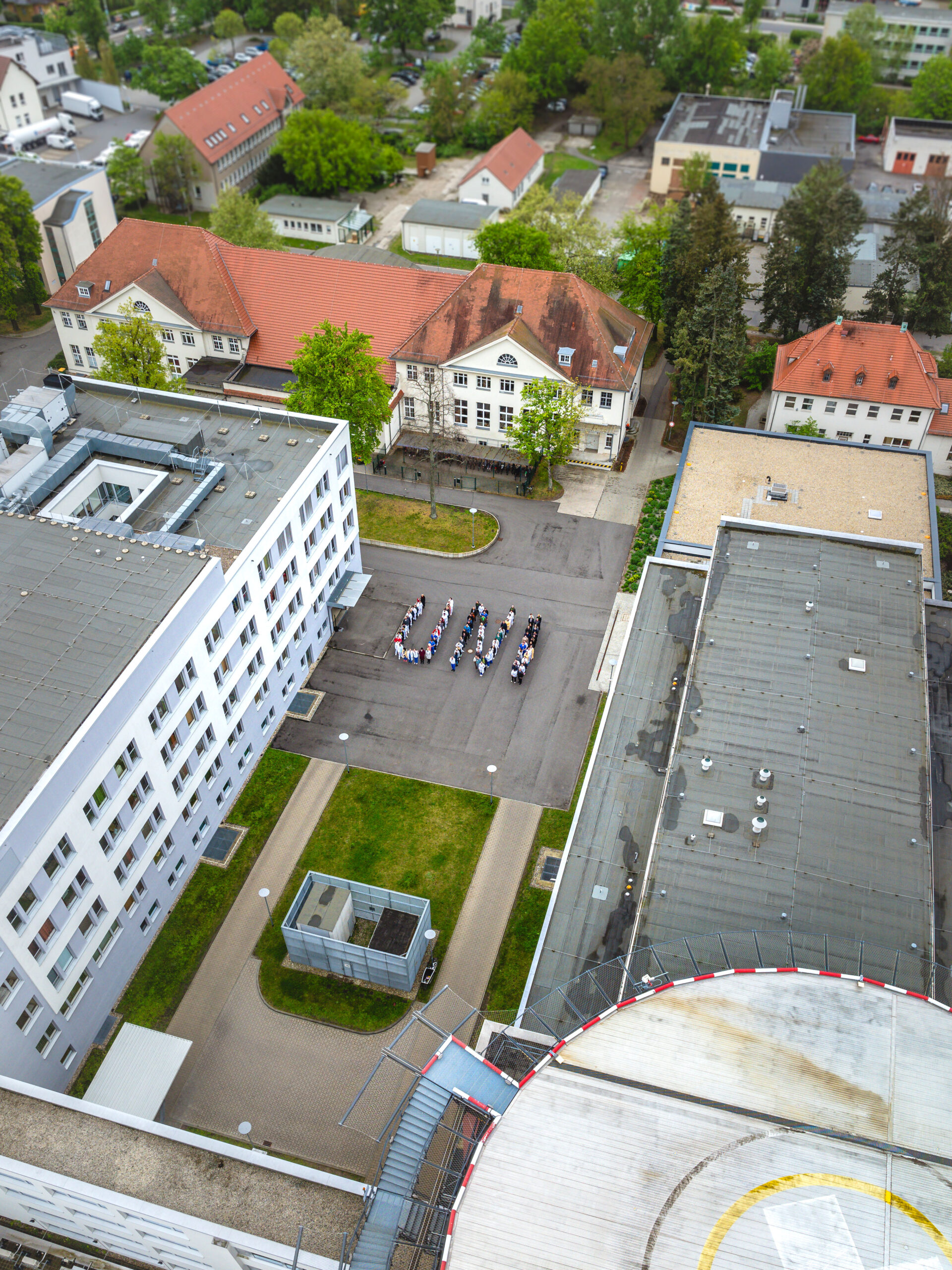 Foto Uni Gruppenbild Das Foto zeigt eine Gruppe von Menschen von oben, die gemeinsam das Wort "UNI" bilden.