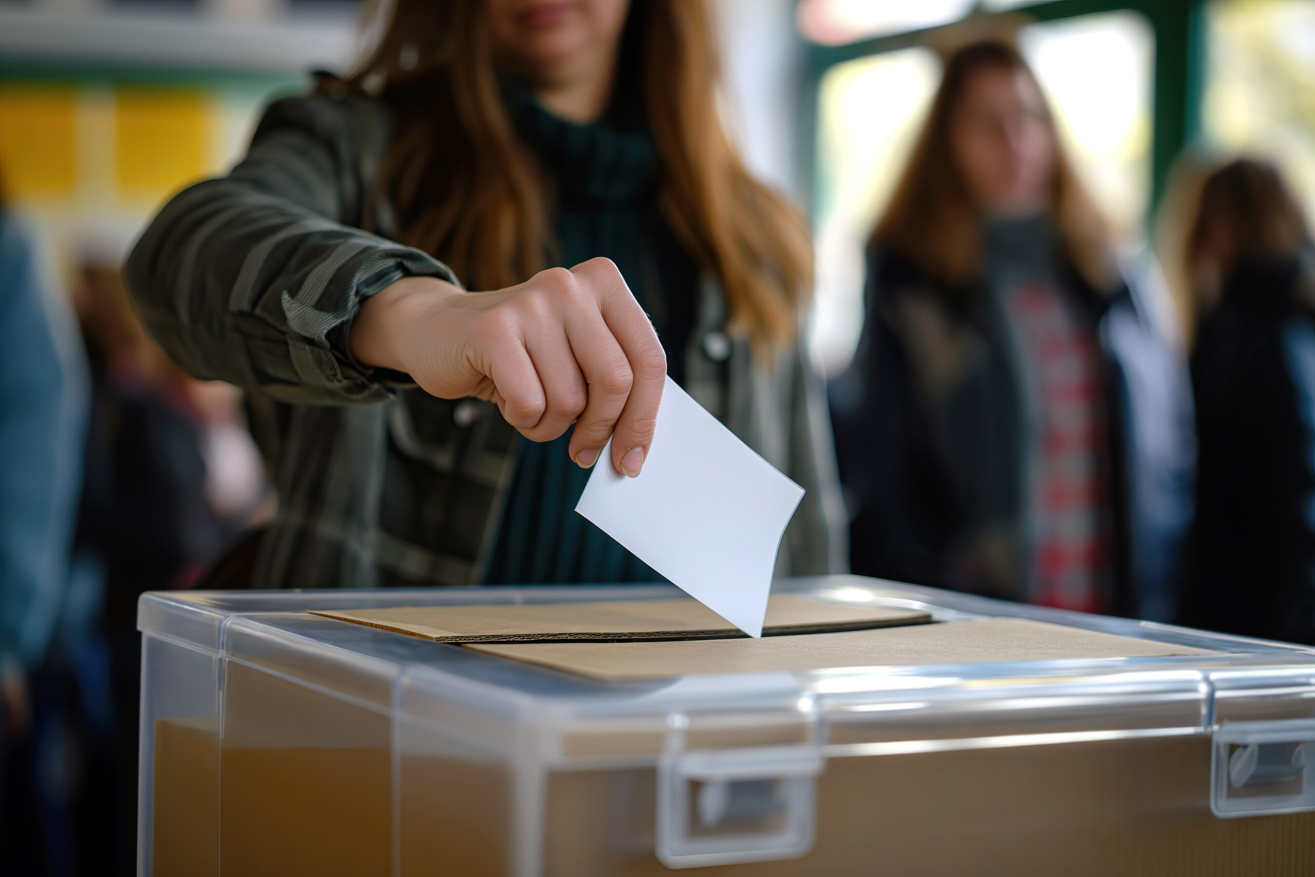 Person Depositing Voting Card Into Ballot Box for Casting Vote in Democracy Eine Frau wirft ihren Wahlzettel in eine Wahlurne.