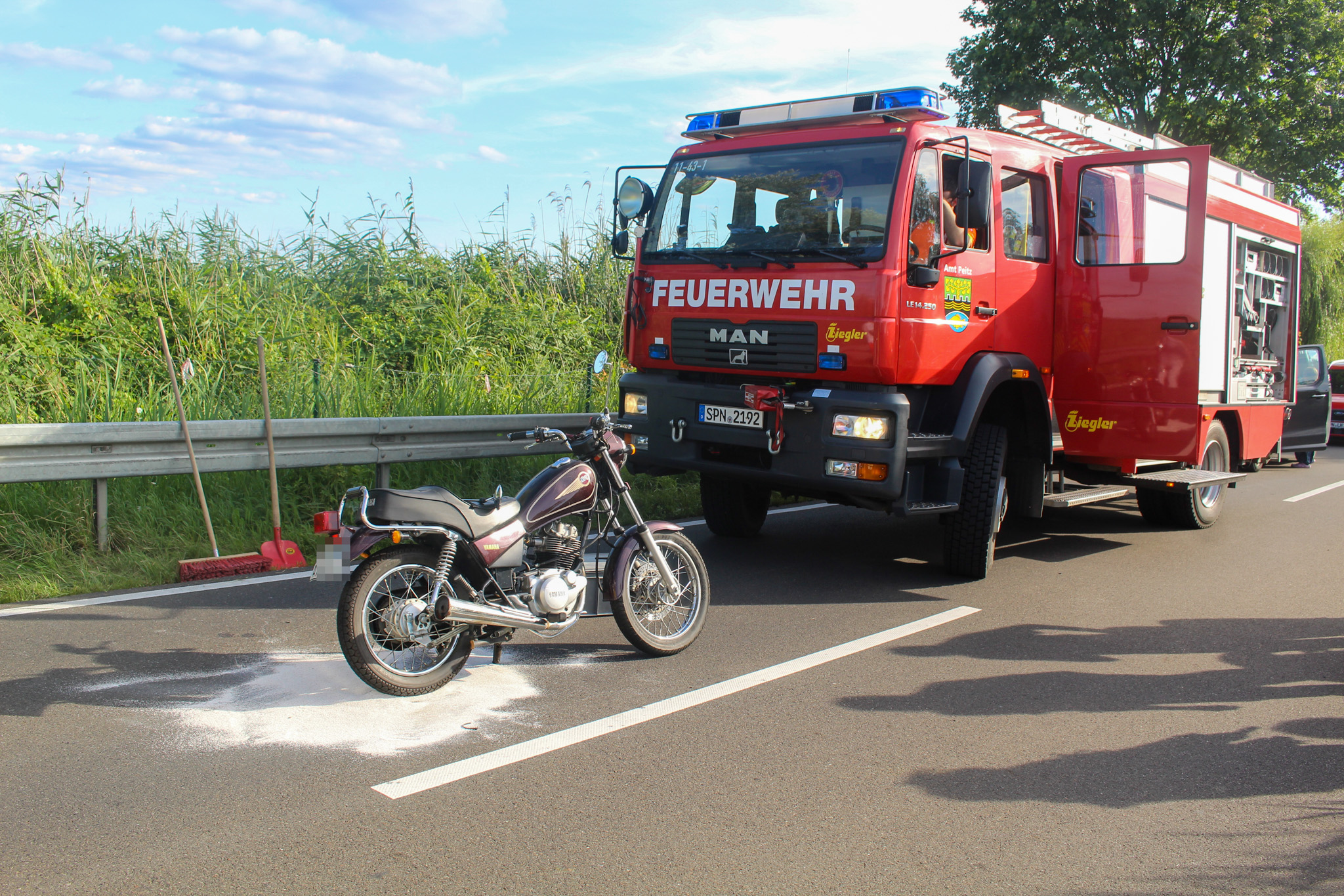 Das Foto zeigt Unfall-Motorrad und Feuerwehr.