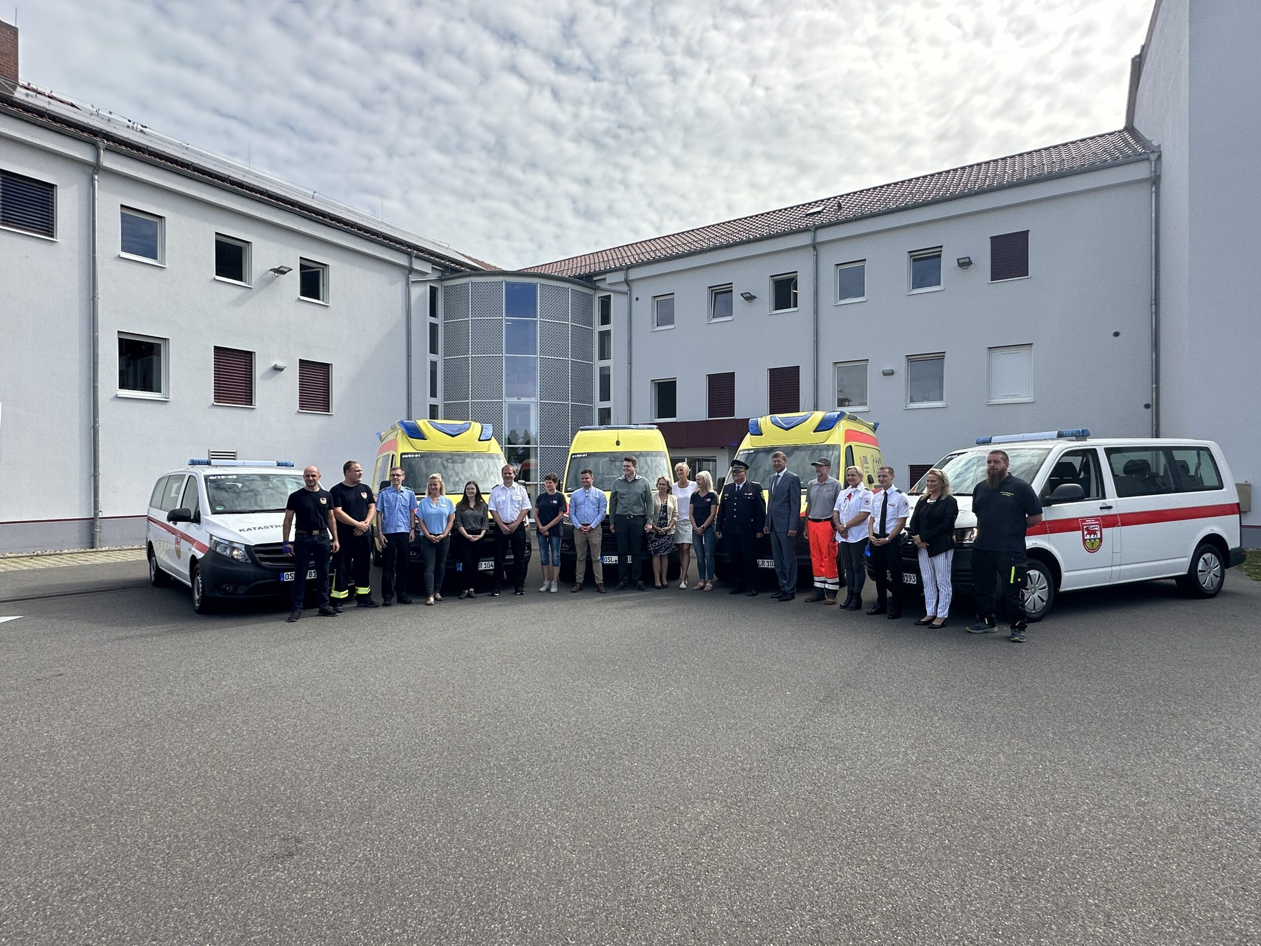 Das Foto zeigt fünf neue Fahrzeuge und Mitarbeitende des Rettungsdienstes im Landkreis OSL.
