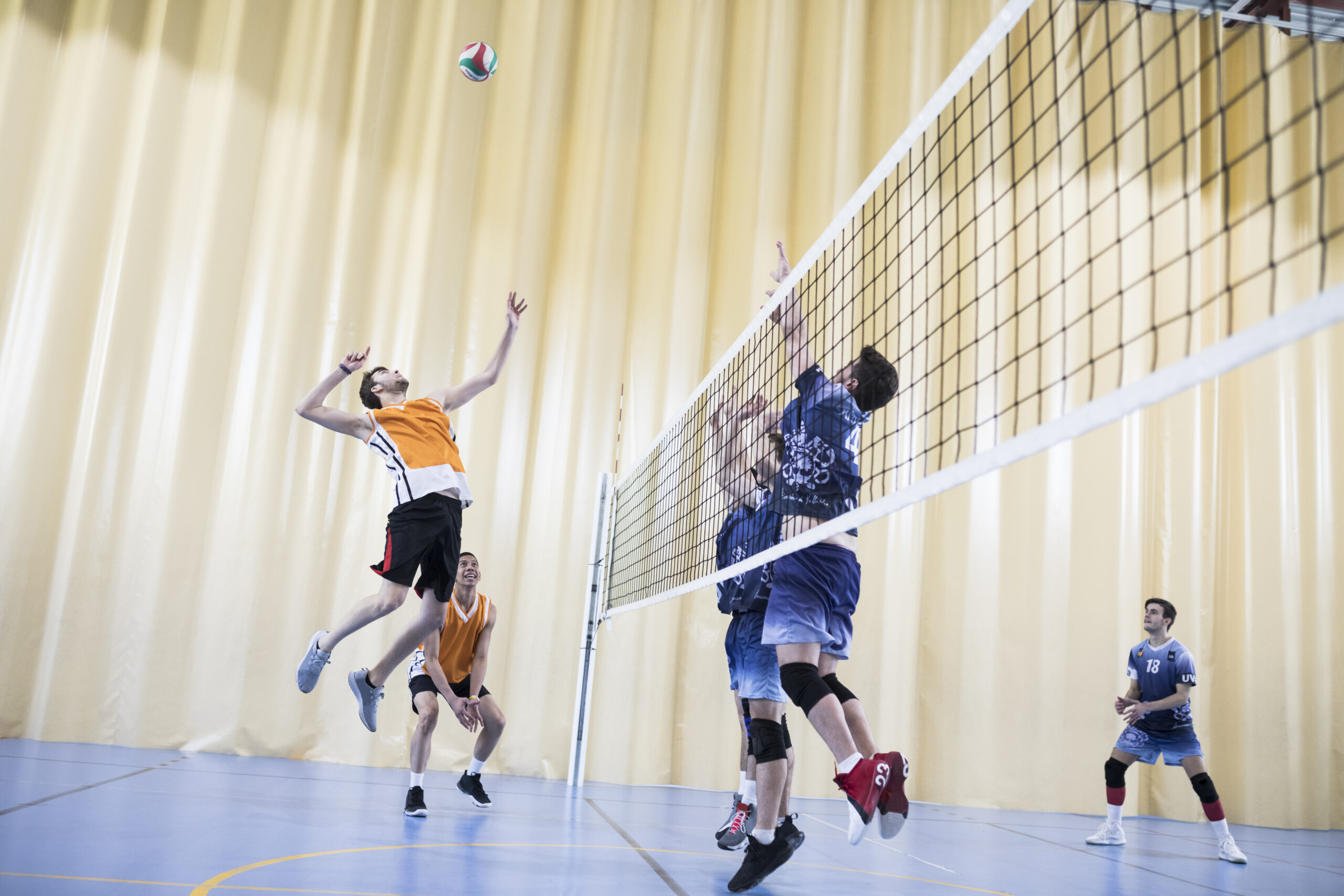 Man jumping during a volleyball match Das Foto zeigt zwei Teams beim Volleyball. Ein Mann springt hoch, um den Ball zu spielen.