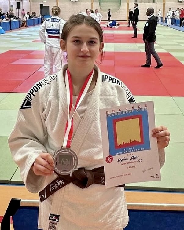 Judo ASAHI Judoka hält Urkunde in der Hand