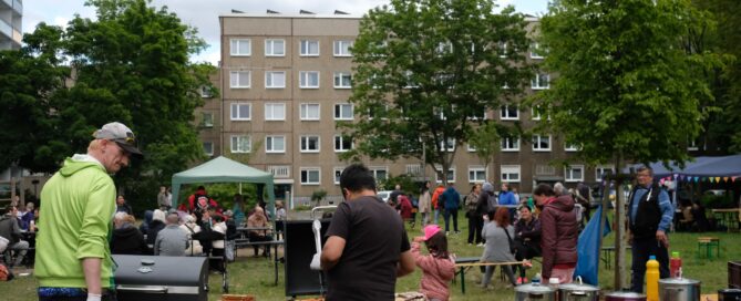Menschen sitzen im Hof und grillen