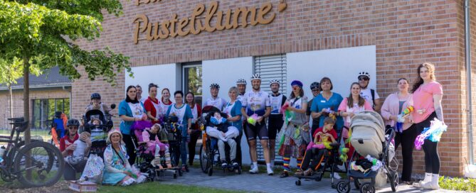 Menschen stehen mit Kindern vor dem Kinderhaus Pusteblume