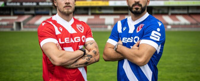 Spieler von Energie Cottbus stehen mit dem neuen Trikot im Stadion