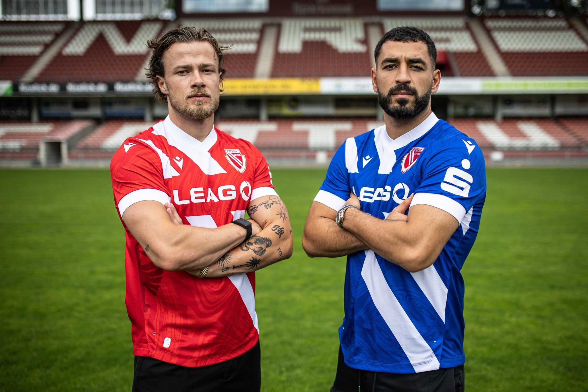 Spieler von Energie Cottbus stehen mit dem neuen Trikot im Stadion