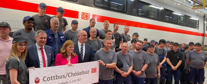 Vor dem ICE wird ein Schild mit der Aufschrift Cottbus hochgehalten