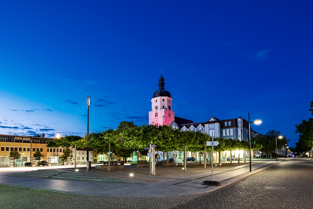 Luebben – Blaue Stunde Das Foto zeigt den Marktplatz von Lübben ohne Straßenbeleuchtung in der Abenddämmerung.