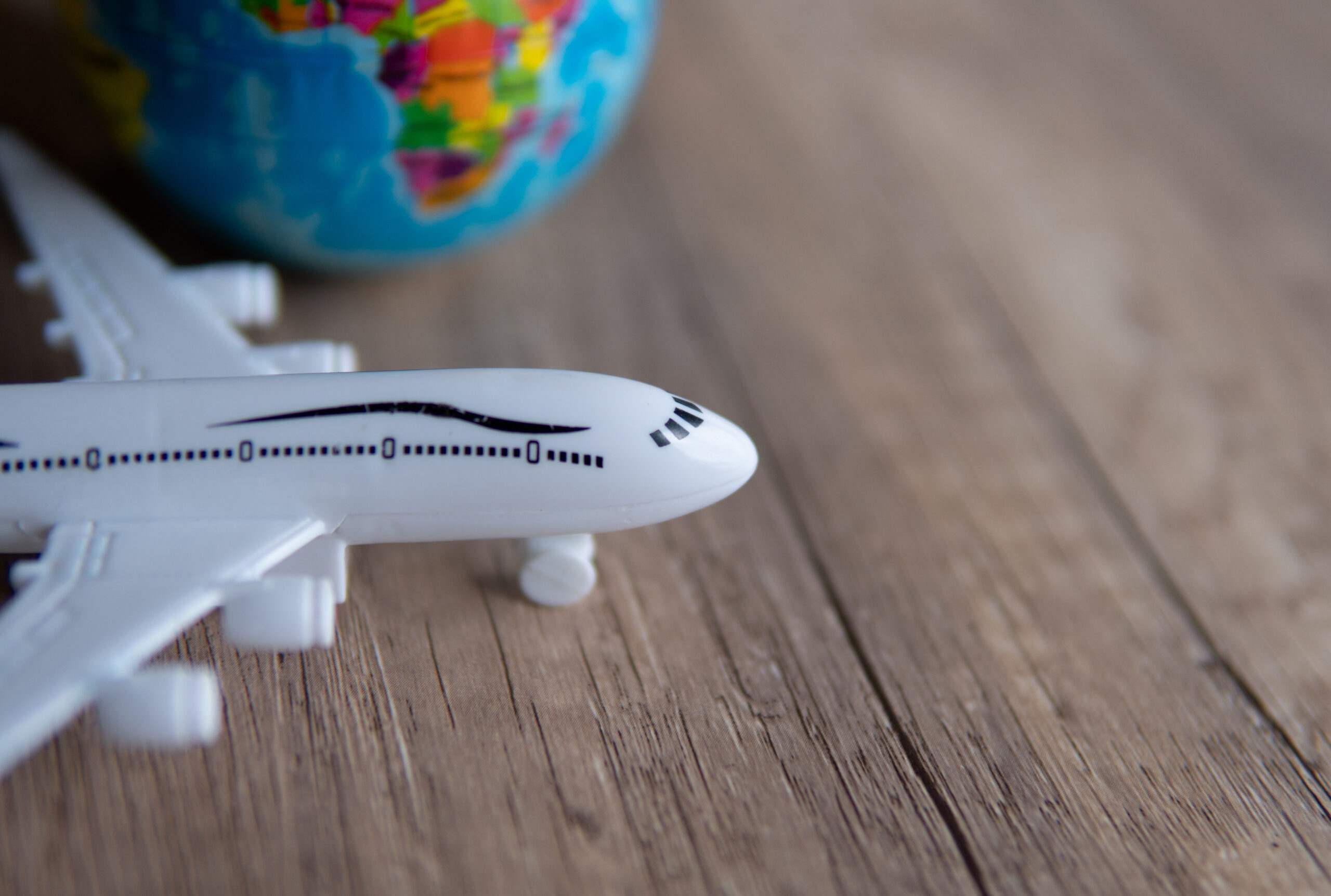 closeup-image-of-toy-plane-and-earth-globe-on-tabl-2025-03-13-17-50-05-utc Das Foto zeigt ein Spielzugflugzeug und im Hintergrund einen Globus.