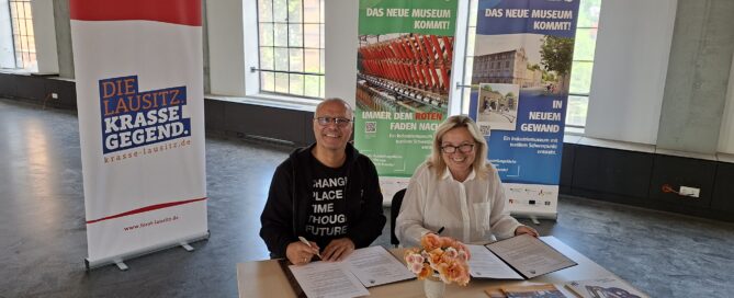 Vertragsunterzeichnung von zwei Personen die am Tisch sitzen
