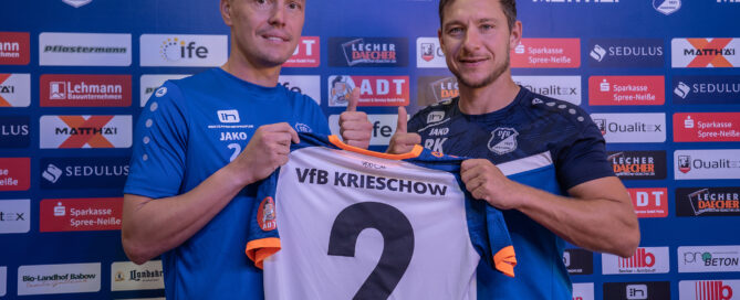 Zwei Spieler halten ein Trikot in die Luft.