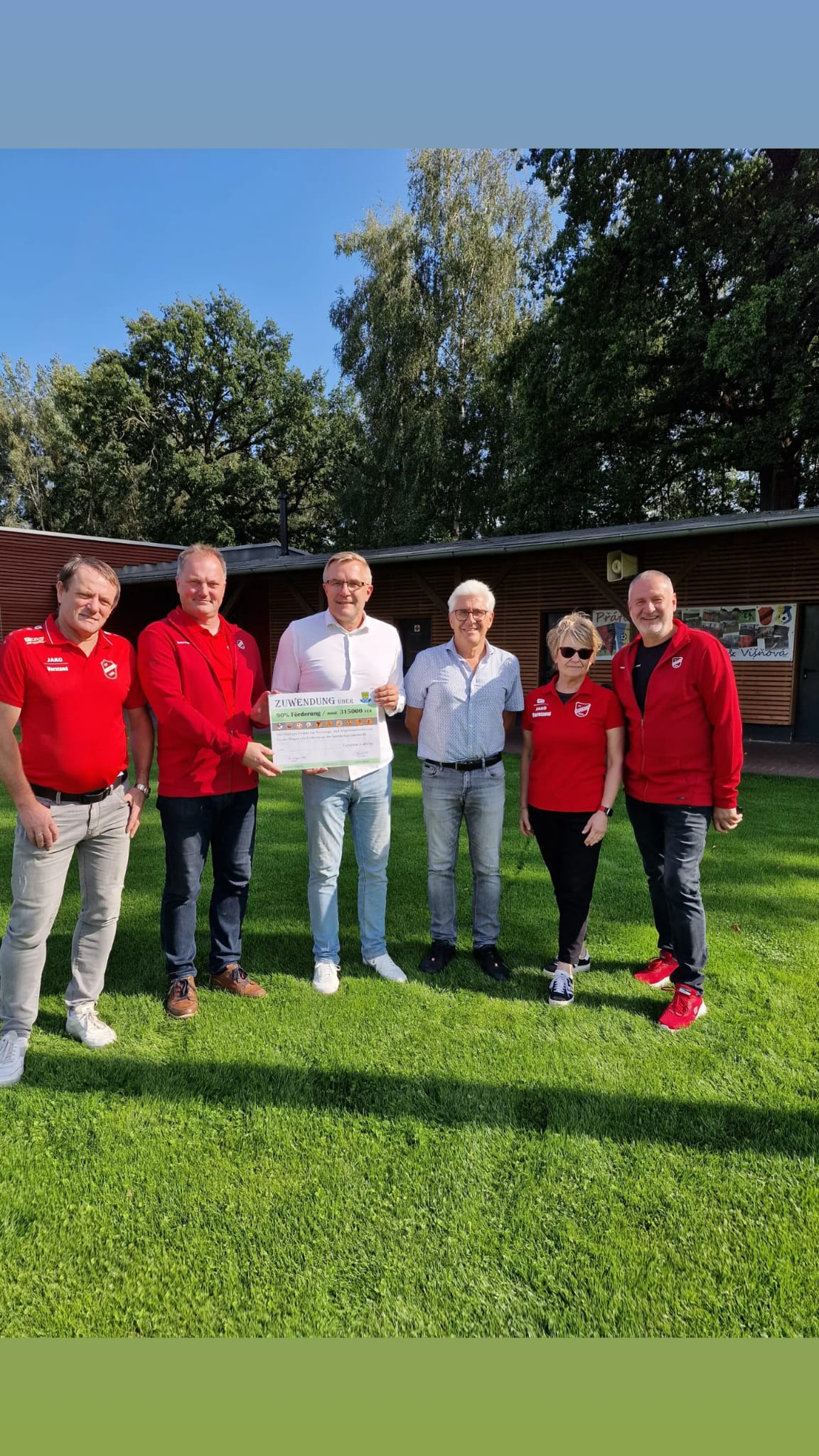 Übergabe Förderung Jahnsportplatz Kolkwitz Auf dem Bild sind Menschen zu sehen. Die einen Scheck hochhalten.