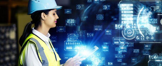 Symbolbild zur Industrie-Arbeit mit Unterstützung durch Künstliche Intelligenz. Eine Frau in Helm und Warnweste betrachtet Datensätze.
