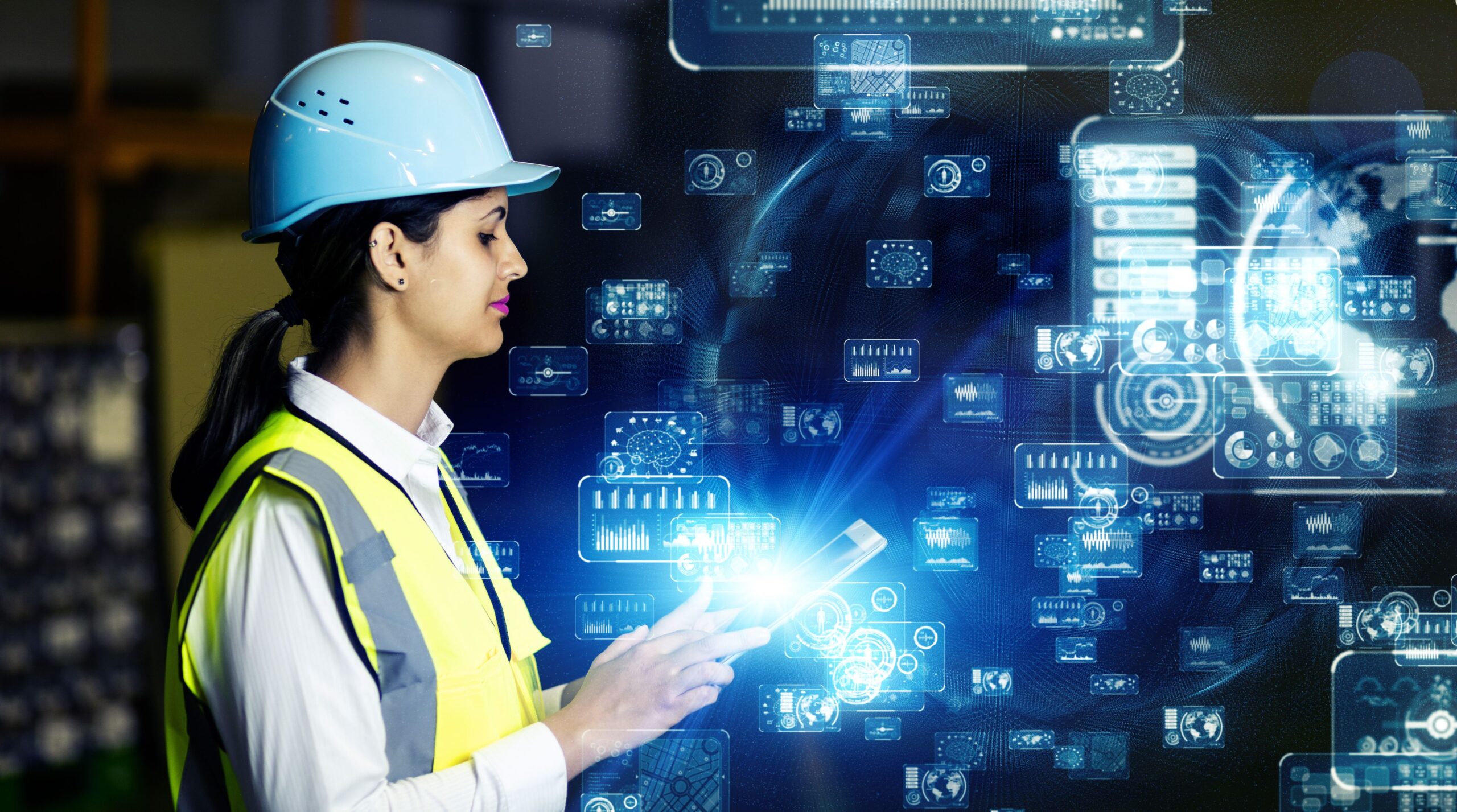 Symbolbild zur Industrie-Arbeit mit Unterstützung durch Künstliche Intelligenz. Eine Frau in Helm und Warnweste betrachtet Datensätze.