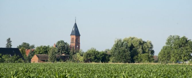 Ein Landschaftsbild aus der Lausitz mit einem Dorf und einer Kirche.