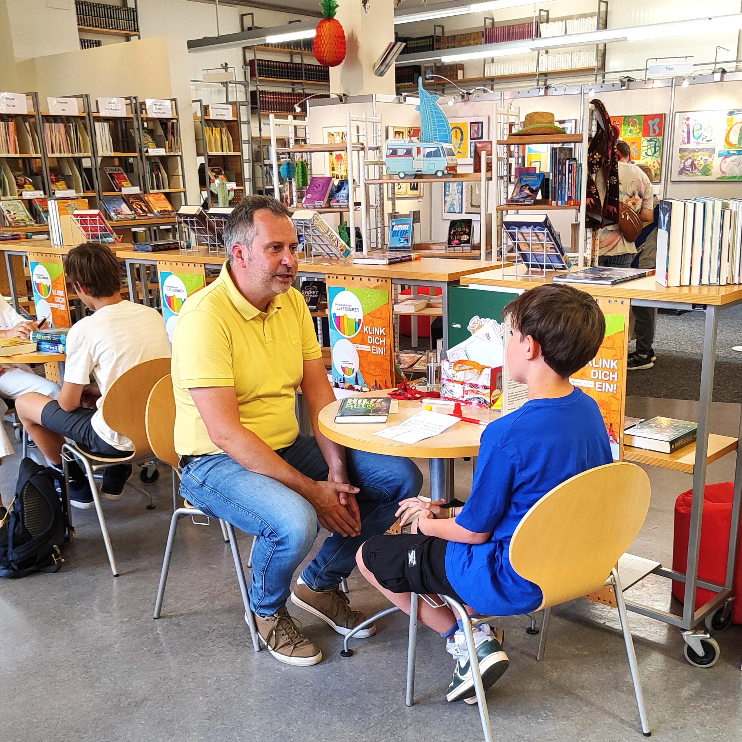 v.l. Oberbürgermeister Tobias Schick beim BLS im Gespräch mit Anton Wedemeier 03, c Juliane Ahrens OB Tobias Schick spricht beim Lesesommer in der Bibliothek mit einem Teilnehmer.