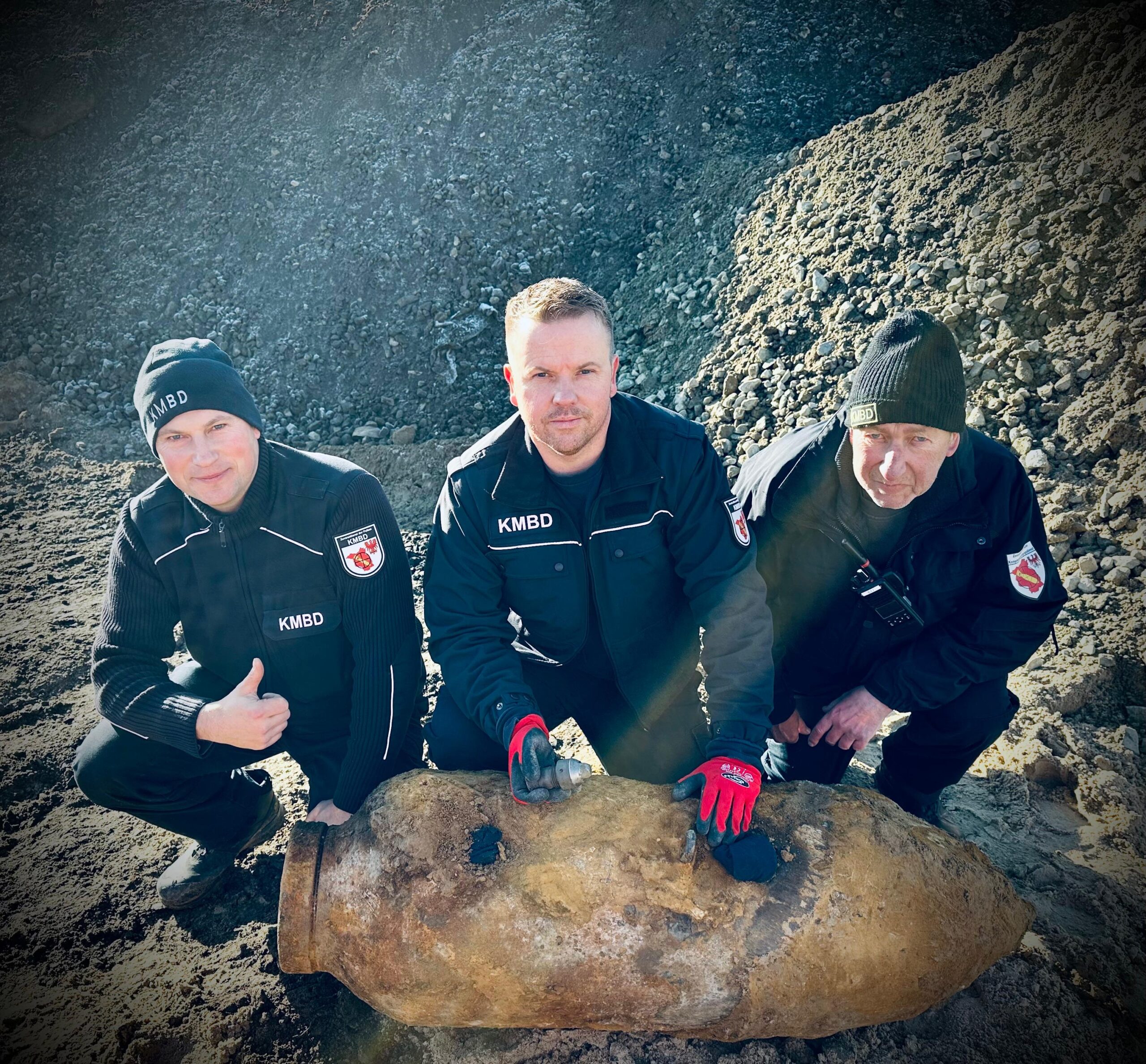 Männer hocken vor einer entschärften Bombe