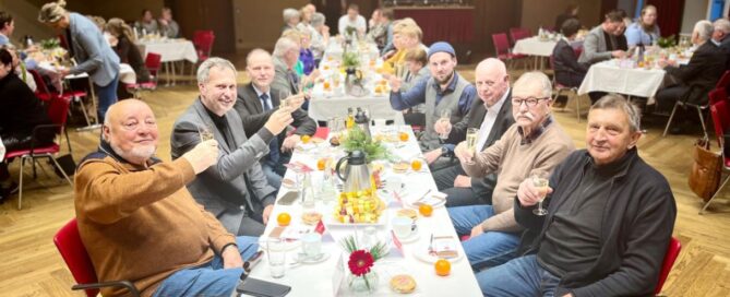 Menschen sitzen an einer gedeckten Tafel