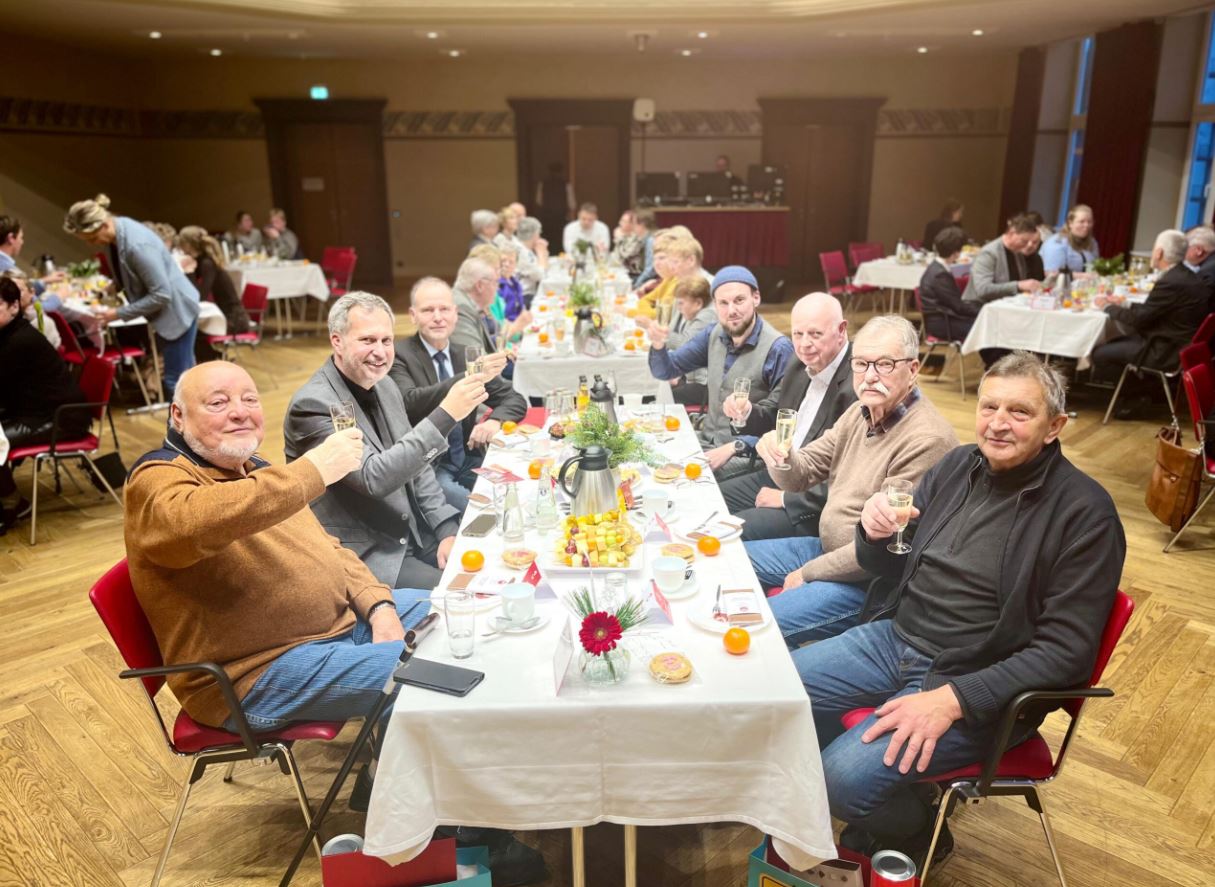 Menschen sitzen an einer gedeckten Tafel