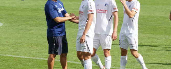 Ein Trainer steht mit Spielern auf dem Fußballplatz