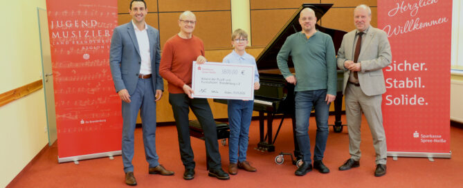 Menschen stehen nebeneinander und halten einen Scheck hoch