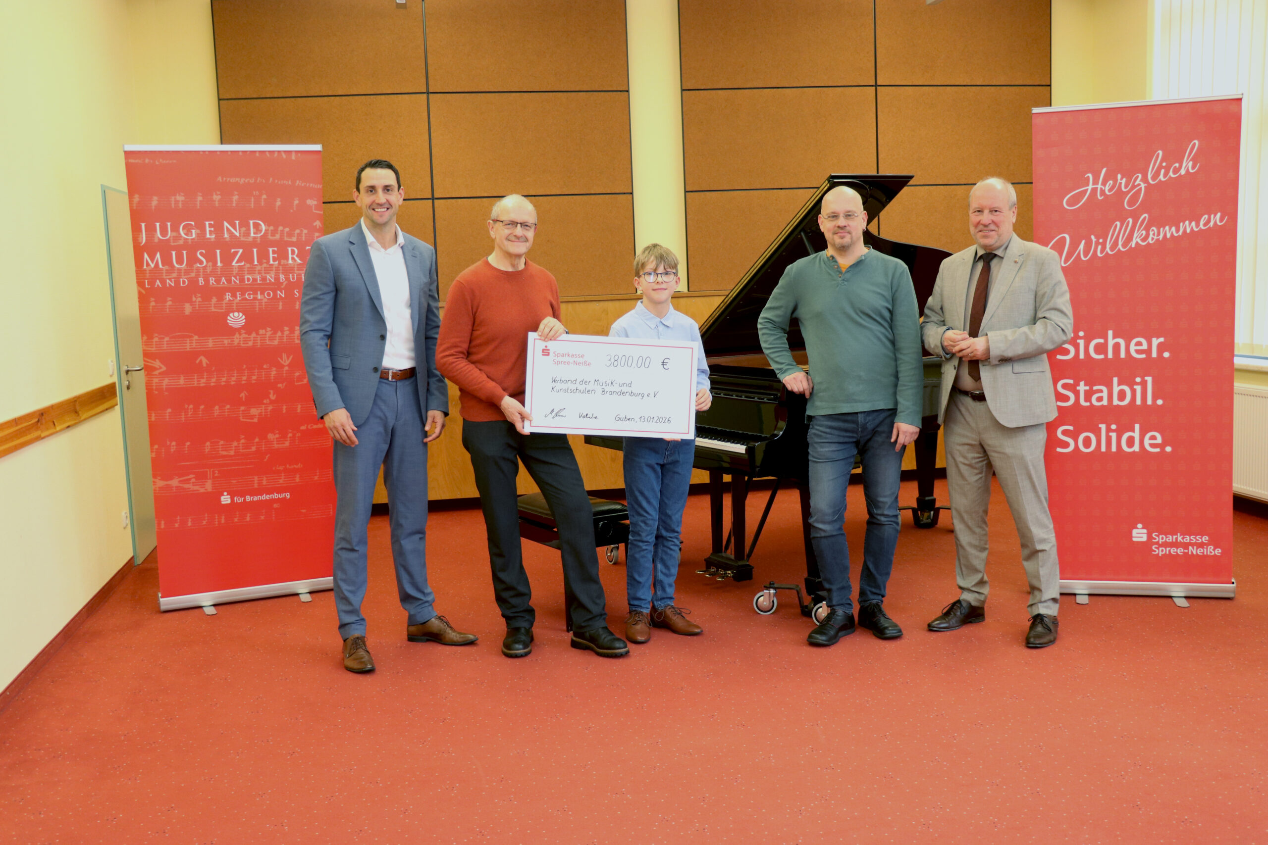 Menschen stehen nebeneinander und halten einen Scheck hoch