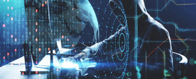 Das Symbolbild zeigt einen Hacker in Kapuzenpulli vor einem Bildschirm.