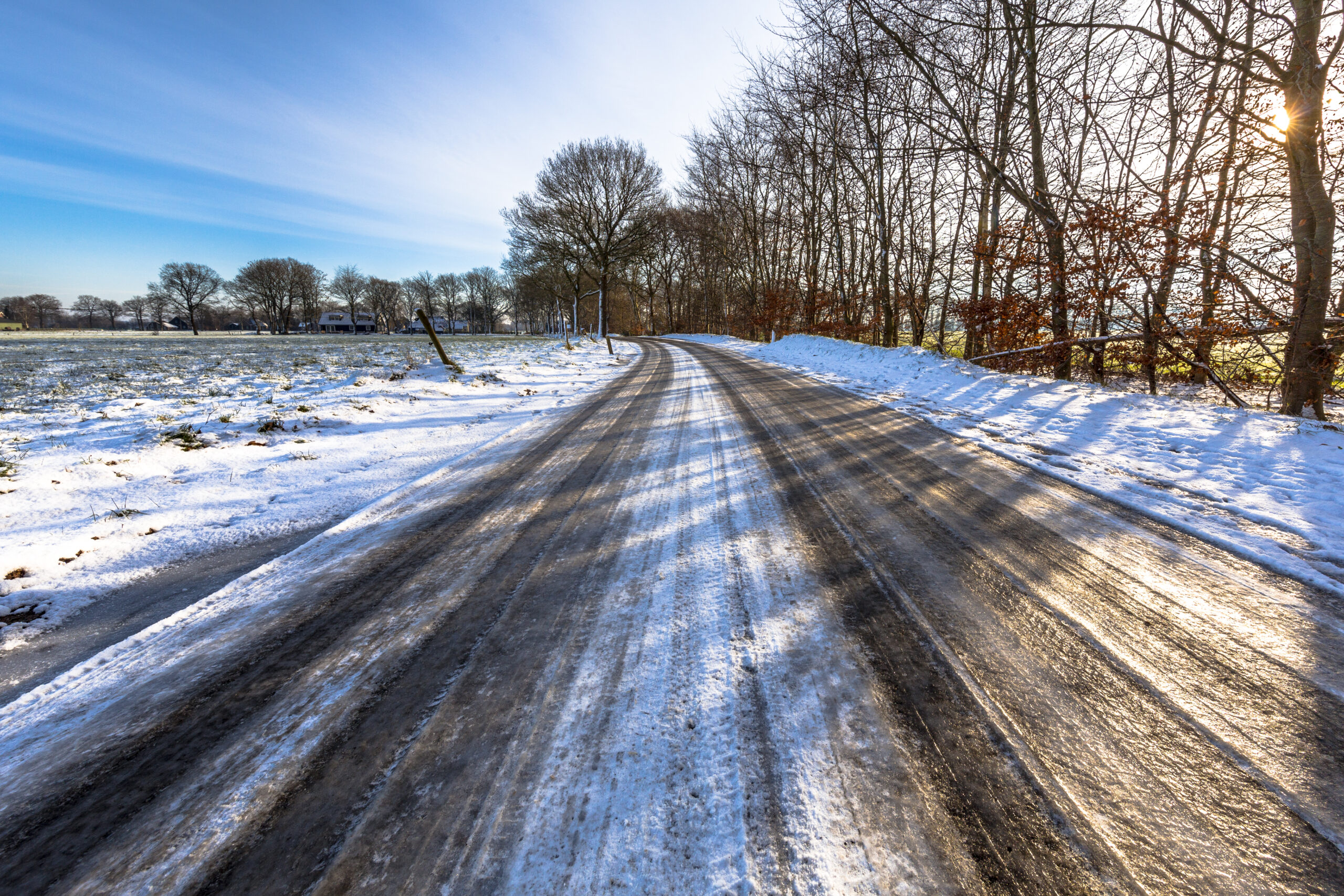 Eine Landstraße mit vereister Fahrbahn und Schnee.