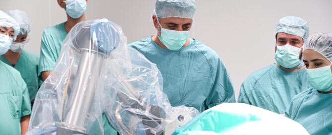 Das Foto zeigt ein Ärzteteam im OP-Saal mit einem Chirurgie-Roboter im Vordergrund.