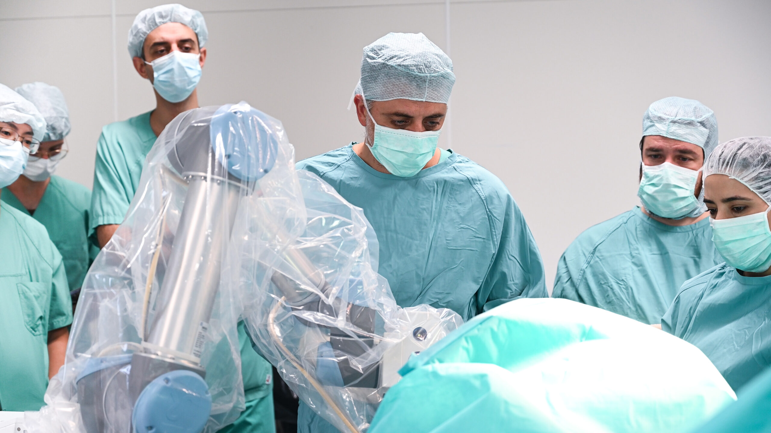 Das Foto zeigt ein Ärzteteam im OP-Saal mit einem Chirurgie-Roboter im Vordergrund.