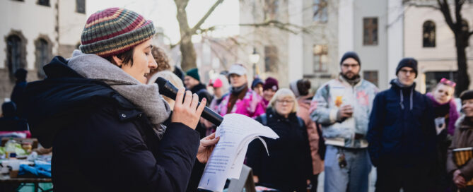 Menschen stehen am Landgericht Cottbus und demonstrieren
