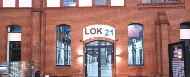 Außenaufnahme von einem roten Gebäude wo Lok 21 oben steht