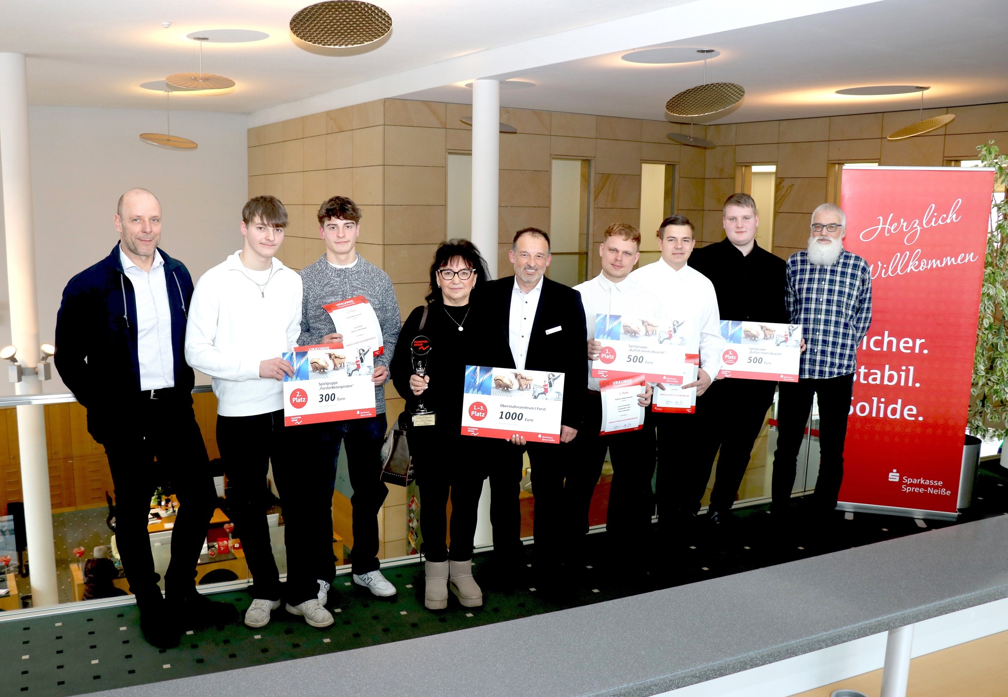 Planspielbörse Junge Menschen stehen nebeneinander und halten einen Scheck hoch