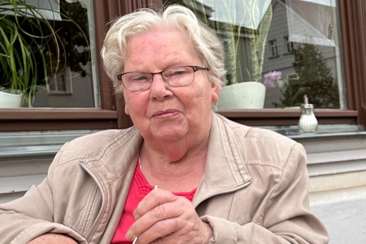 Eine Rentnerin mit Brille sitzt am Tisch