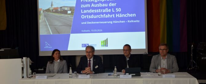 Vor eienr Tafel sitzen Politiker