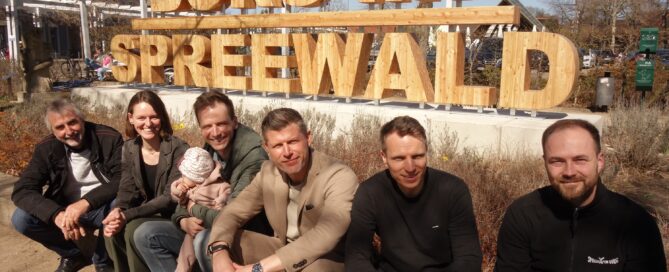 Menschen sitzen vor einem Schriftzug Burg im Spreewald