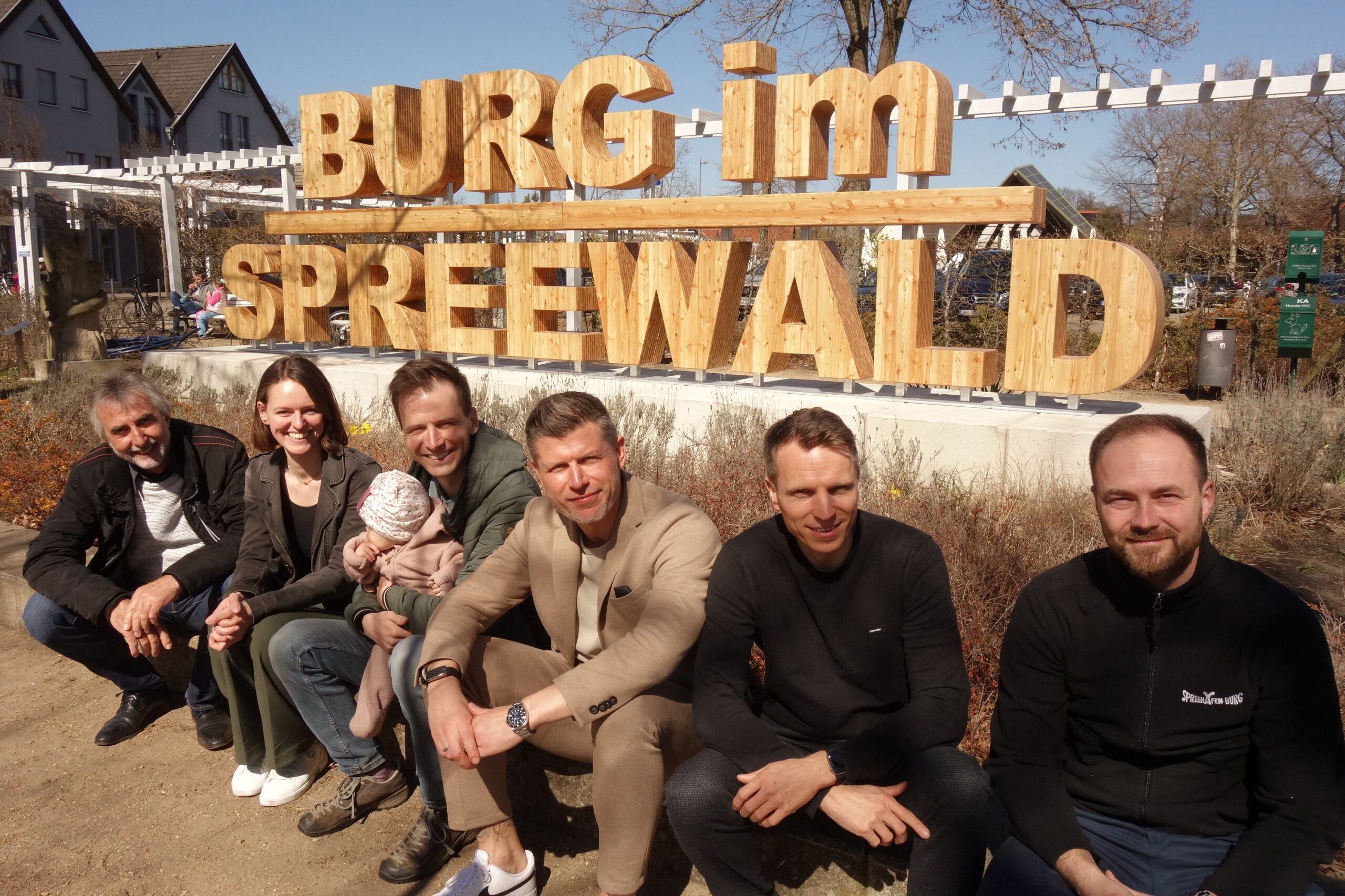 Menschen sitzen vor einem Schriftzug Burg im Spreewald